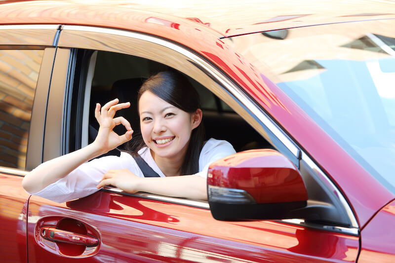車でOKポーズをする女性